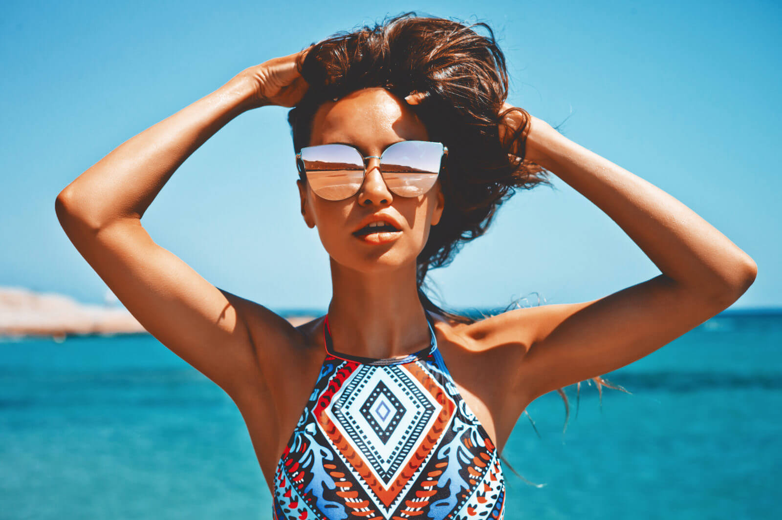 Mulher na praia com oculos de sol espelhado